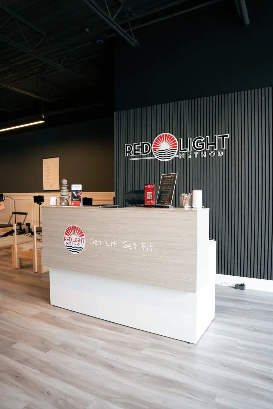 The front desk at Red Light Method in Commack, with the studio's logo on a dark slatted wall
