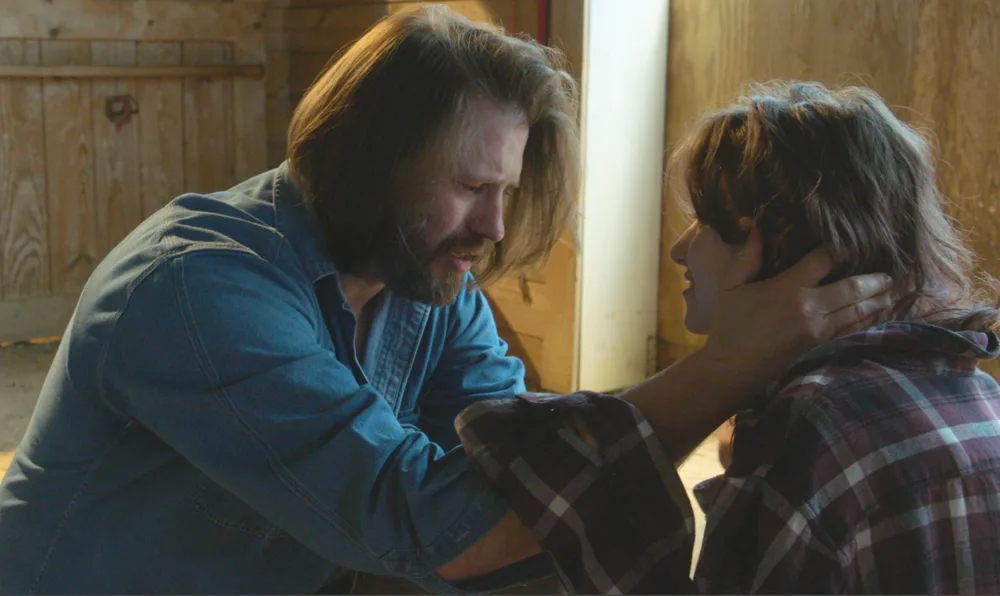 A father holding his son's face in an emotional scene in a barn from To God's Ear