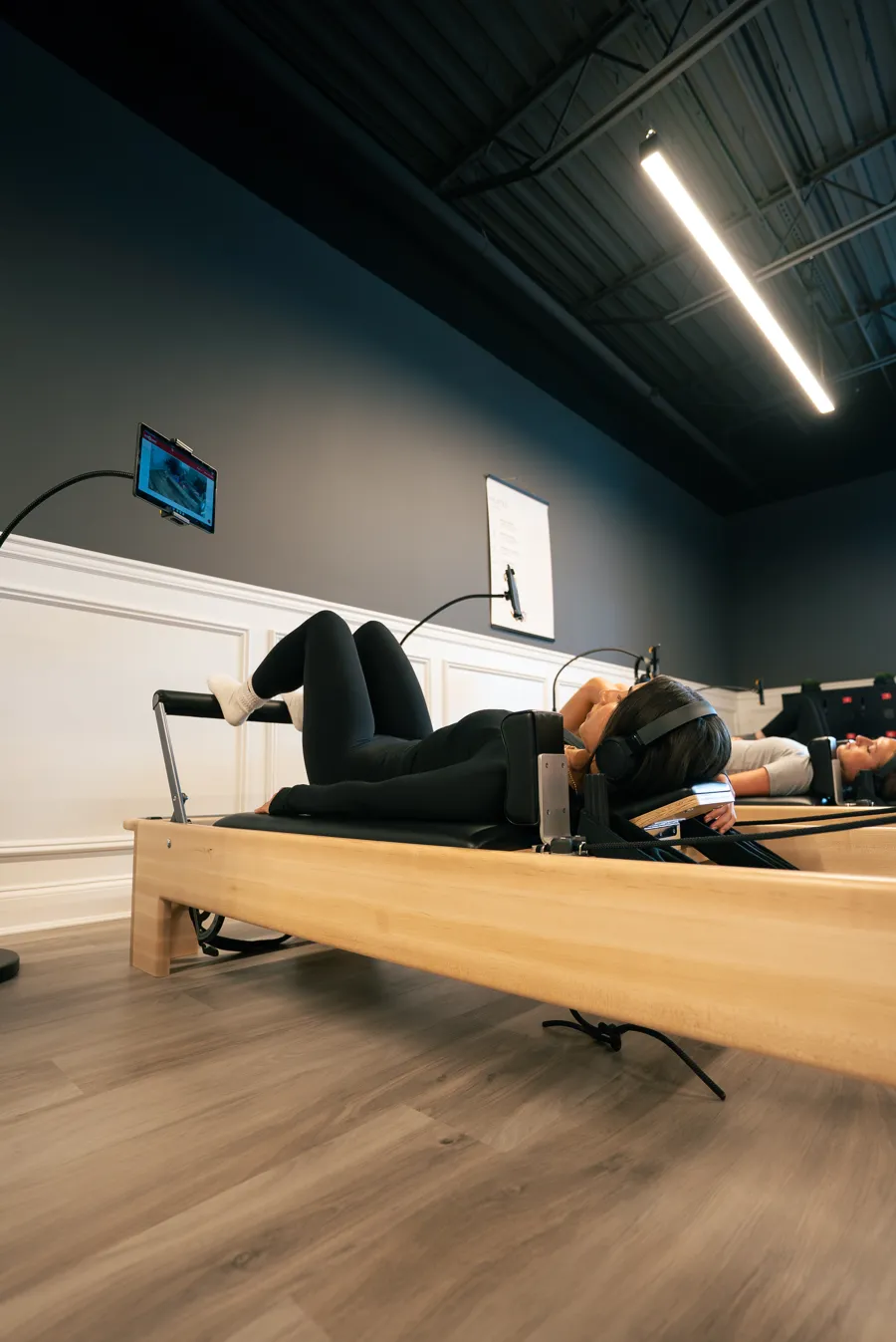 A member on a Pilates reformer at Red Light Method in Commack, guided by a screen at the end of the machine